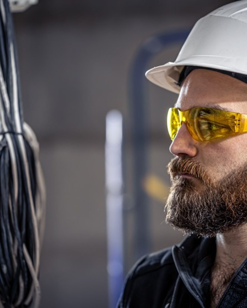 Male electrician at the checkout counter on a blurred background of a switchboard.