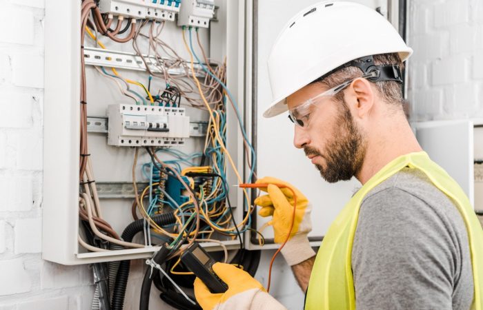 handsome-electrician-checking-electrical-box-with-multimetr-in-corridor-e1624860078476.jpg