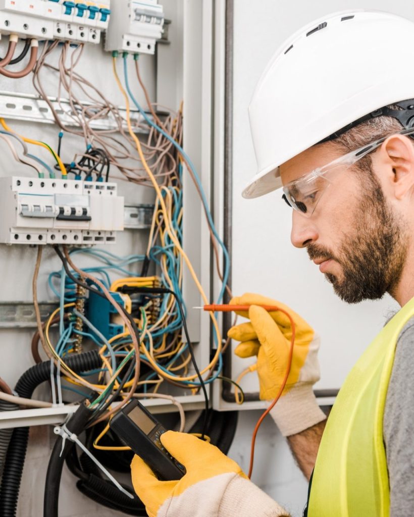 handsome-electrician-checking-electrical-box-with-multimetr-in-corridor-e1624860078476.jpg